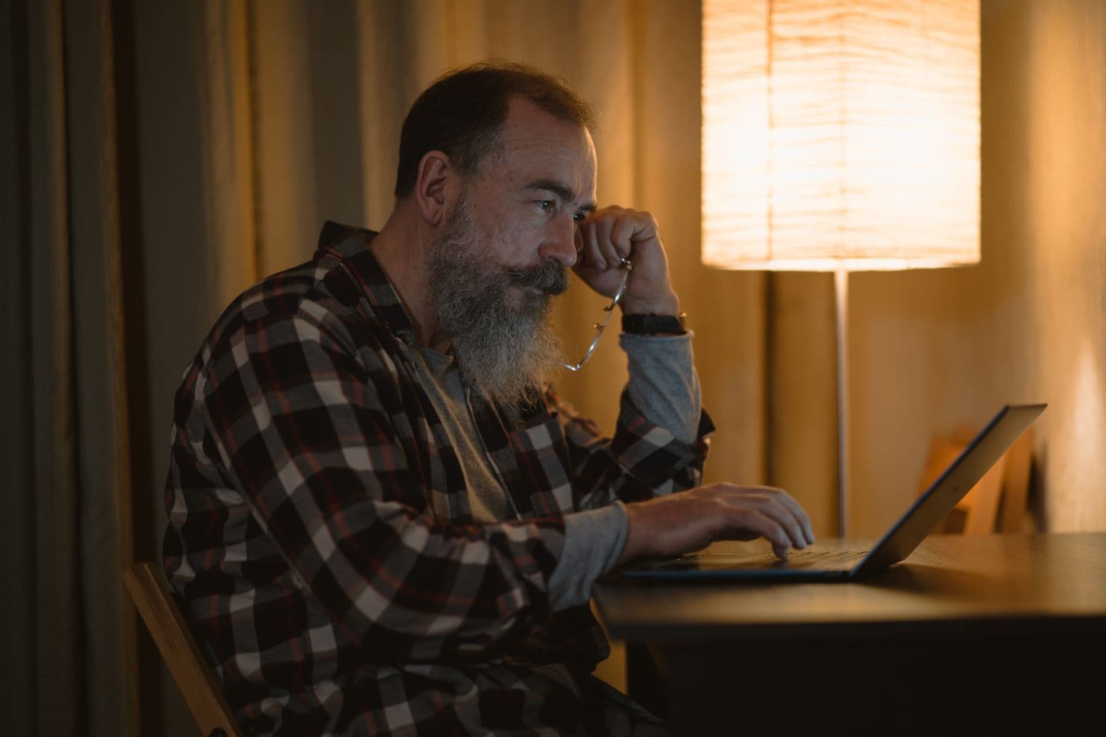 A clinician working on a laptop late in the evening by lamplight
