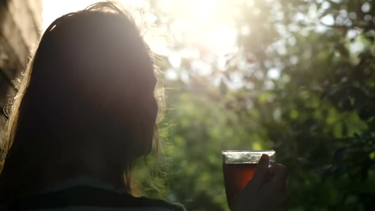 A woman enjoying a cup of tea outdoors in golden evening light